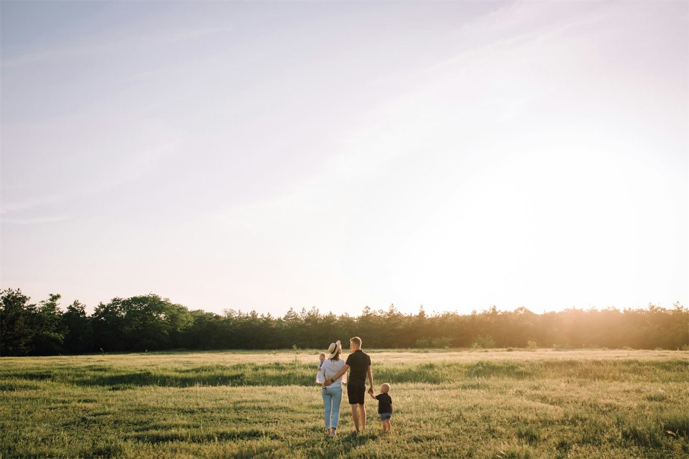 Un couple et son enfant marchent dans un champ au coucher du soleil, photographie de Camille & Théo.